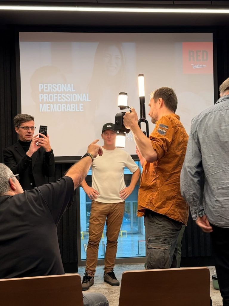 One man holding a handheld rig holding a scanning camera with a light above and below it, while 3 others stand and look on. Bushman Panoramic Halo 360 lights are featured in the image.