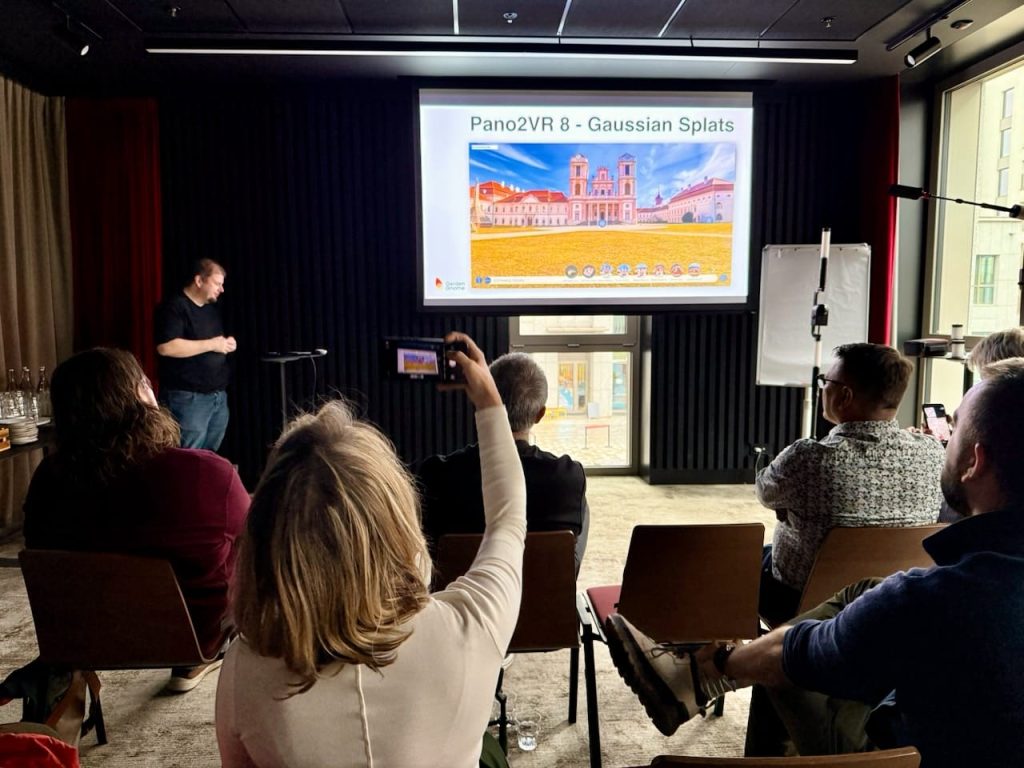 Thomas Rauscher, CEO of Garden Gnome, GmbH, is seen giving a presentation to an audience. The slide that is visible says, Pano2VR 8 - Gaussian Splats.